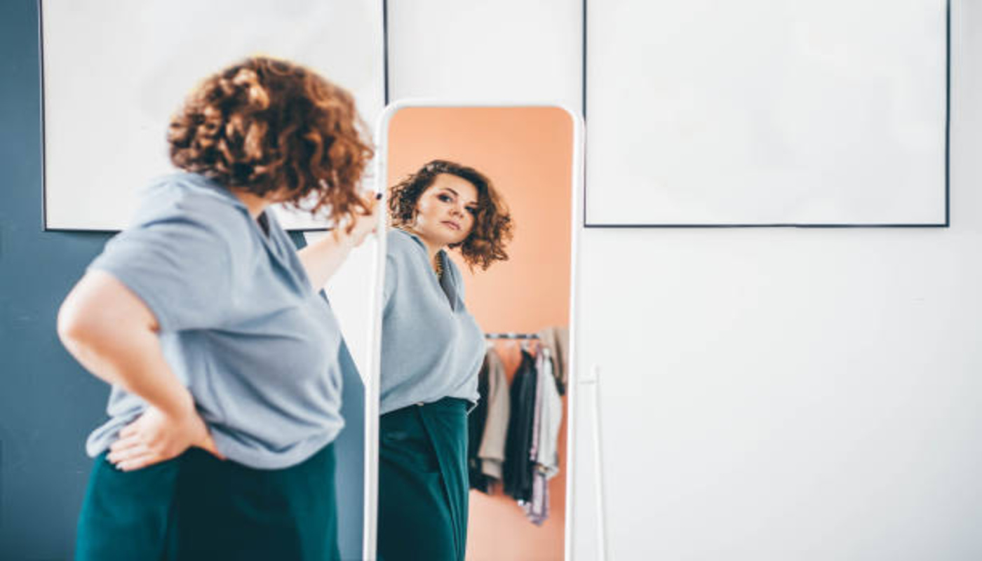 https://media.gettyimages.com/id/1369562988/photo/overweight-young-woman-in-glasses-admires-choice-of-clothes-standing-in-front-of-large-mirror.jpg?s=612x612&w=0&k=20&c=70-pyt87U8fWqhiiz0VH40q1Y5k1GtQfiA46PaNaY0A=